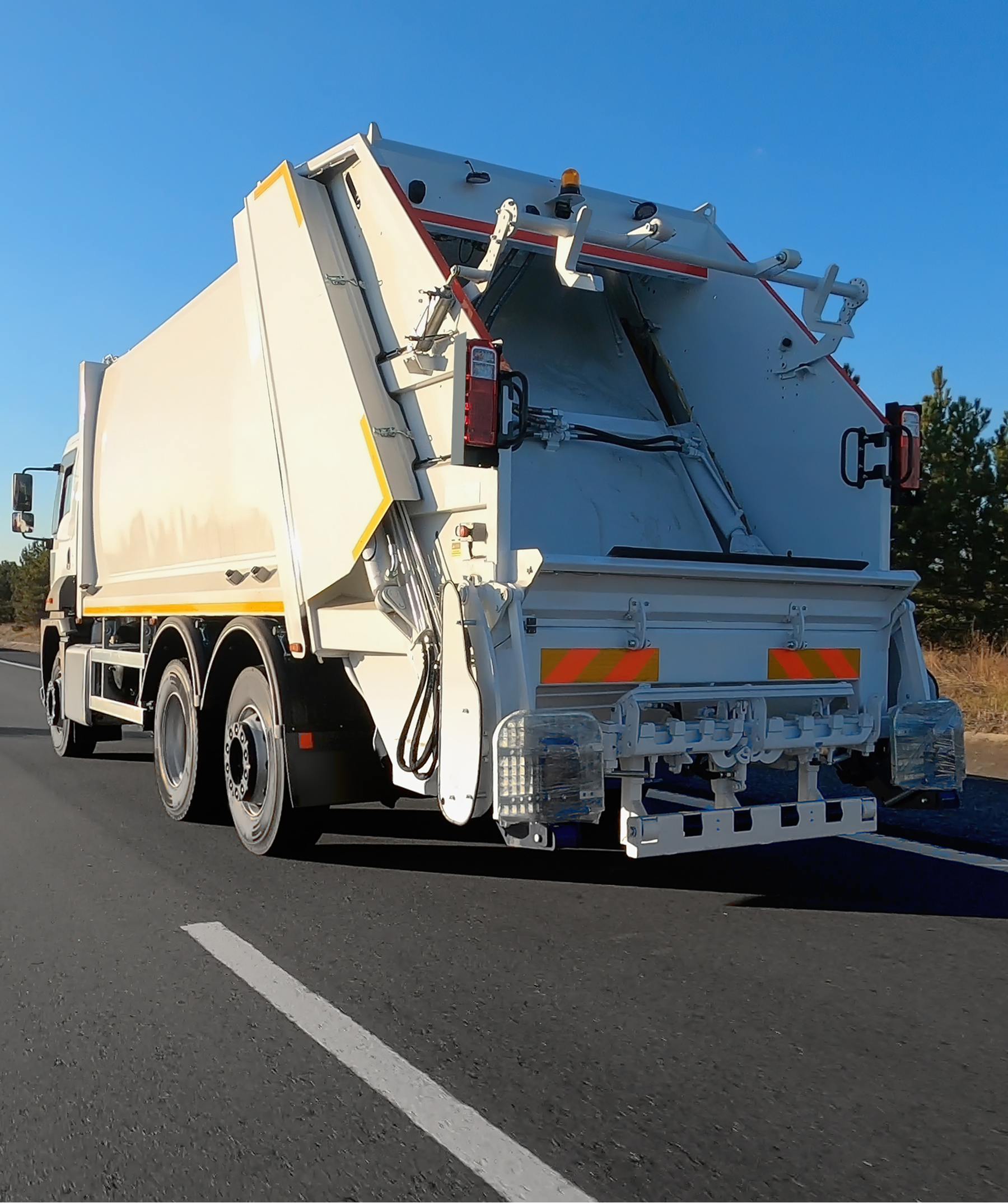 Garbage truck driving on a clear road.