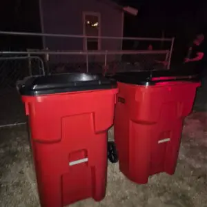 Two red outdoor trash bins with black lids